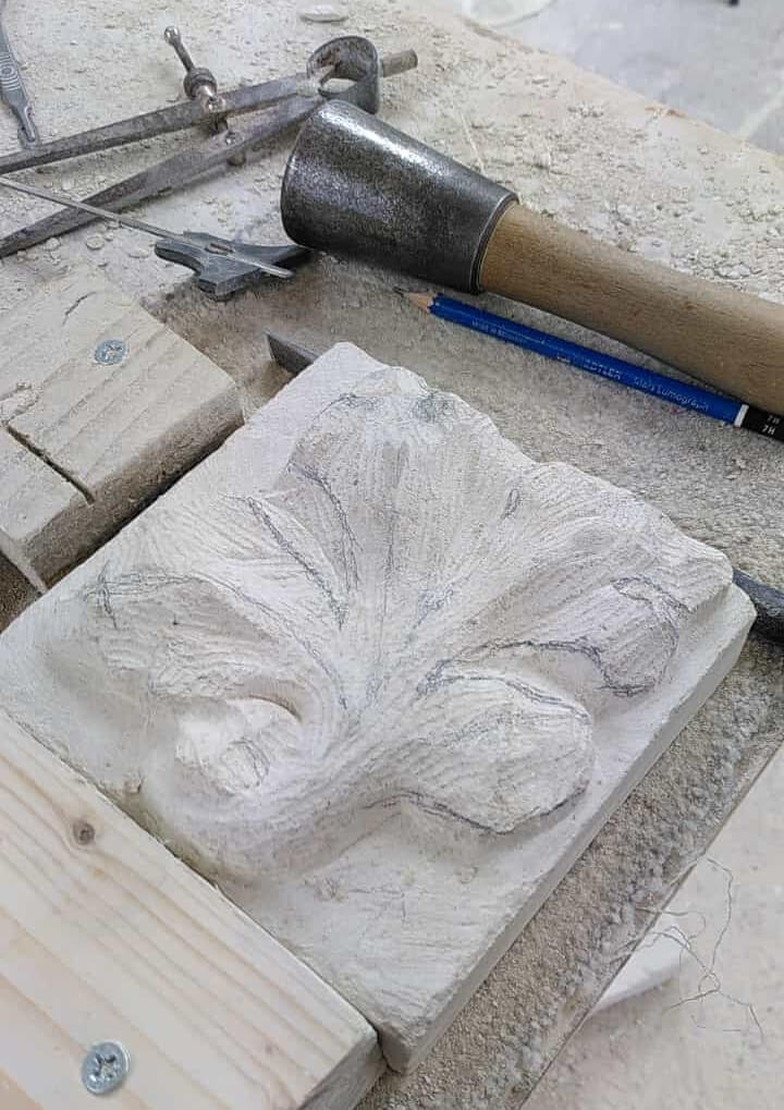 Subtle curves carved into a lump of Portland stone. Pencil lines mark edges to be refined.